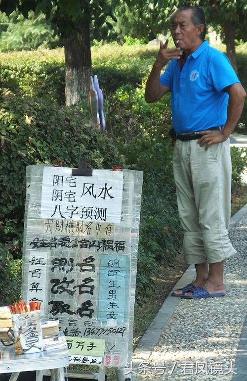 2023年7月27日湖北宜昌高温酷暑数个算命占卜摊摆在公园的树荫下等待