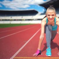 积极的女子赛跑运动员准备田径比赛享受锻炼培养和锻炼在体育场跑道上